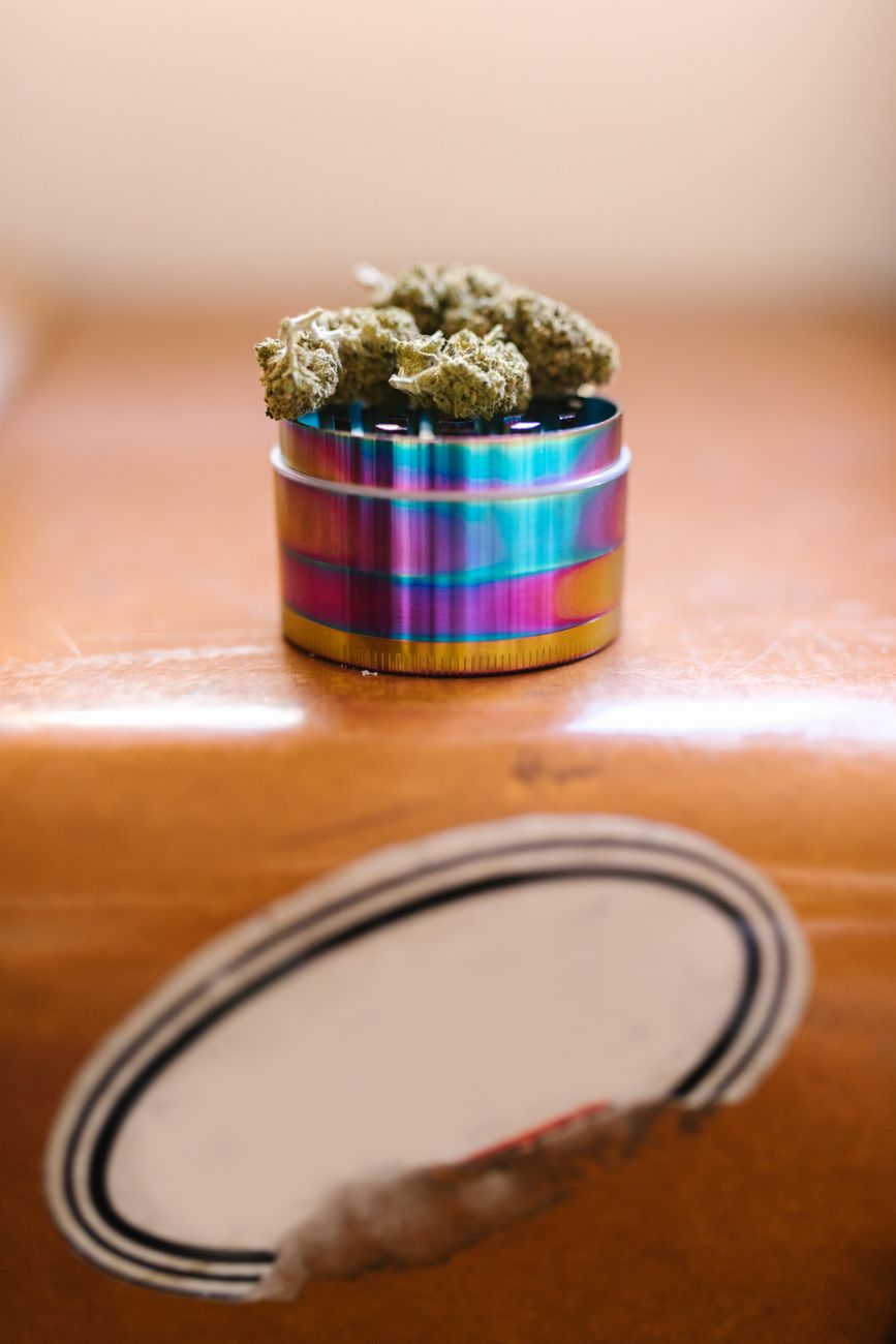 Colorful weed grinder with cannabis buds, shot from above with soft lighting and selective focus.